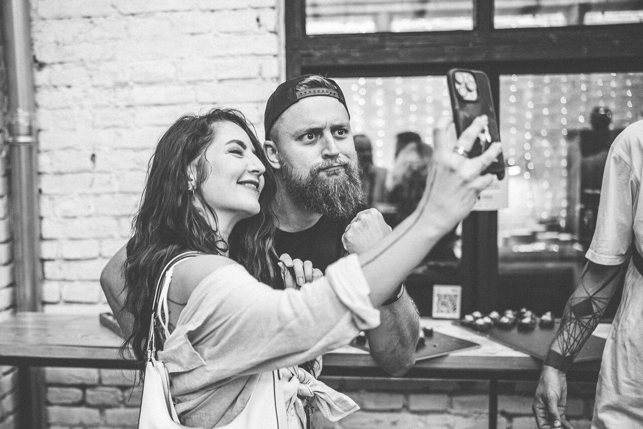 Černobílé selfie dvojice u cihlové zdi na eventu